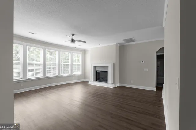 an empty room with wooden floor fireplace and windows