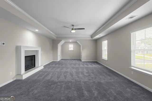 an empty room with windows and fireplace