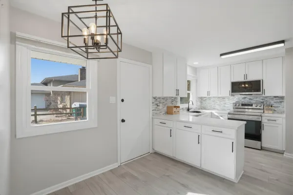 a kitchen with stainless steel appliances granite countertop a sink a stove a microwave a counter top space and cabinets