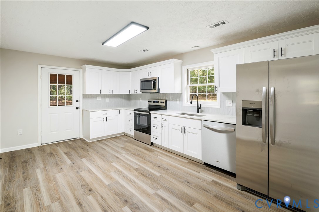 1531 Pughs Store Road Afton, VA 22920 - Photo 11 of 40 a kitchen with white cabinets a sink a window and stainless steel appliances