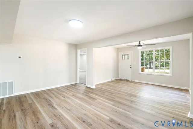 an empty room with wooden floor and windows