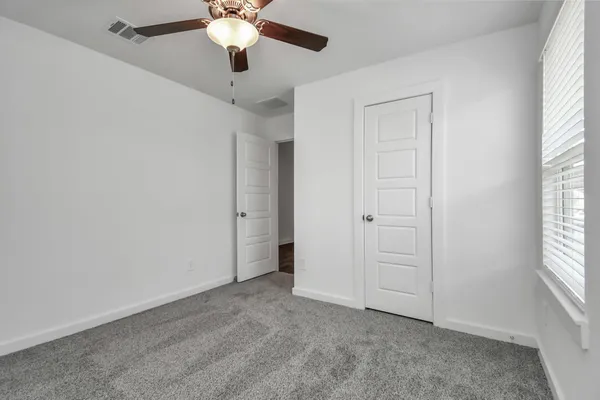 an empty room with a window and a fan