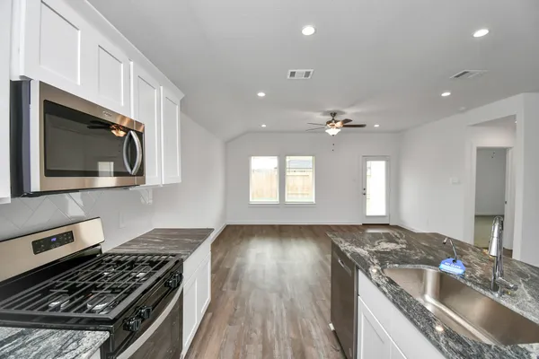 a view of kitchen and kitchen with sink wooden floor and windows