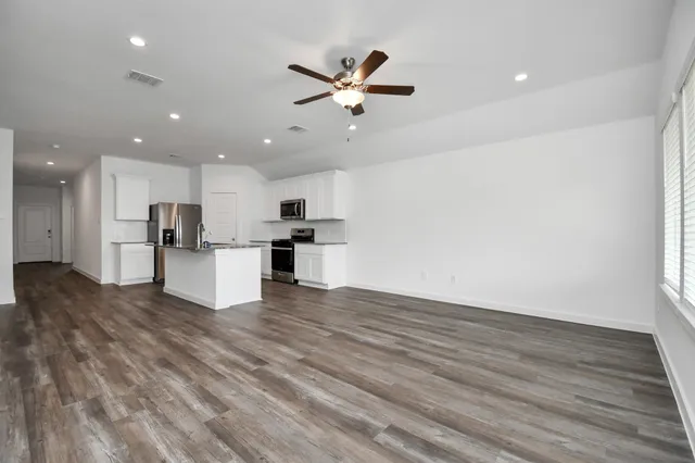 an empty room with ceiling fan and windows