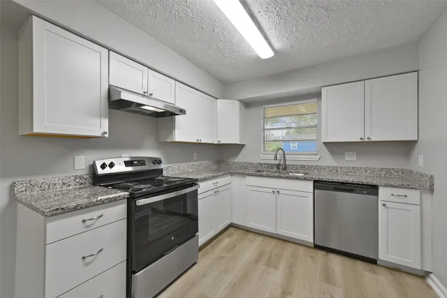 a kitchen with stainless steel appliances granite countertop a sink stove and cabinets