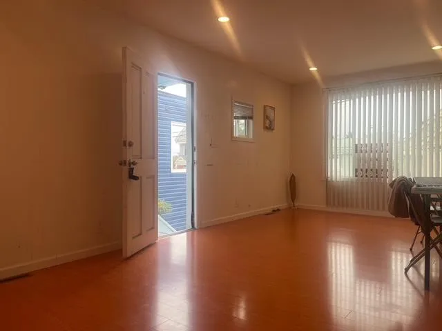 an empty room with wooden floor and windows