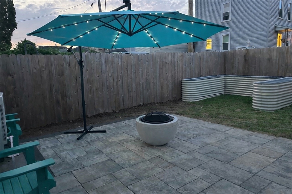 493 Rivet Street New Bedford, MA 02740 - Photo 20 of 20 a backyard of a house with wooden fence and a fire pit