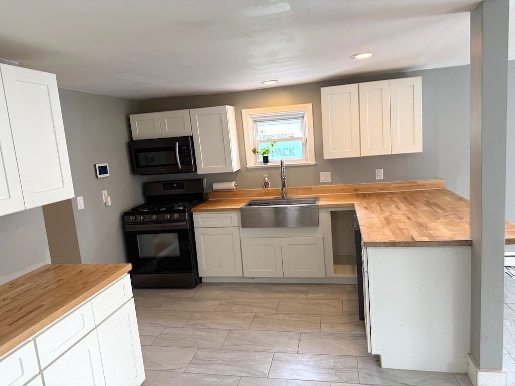 493 Rivet Street New Bedford, MA 02740 - Photo 2 of 20 a kitchen with a stove a sink and a microwave
