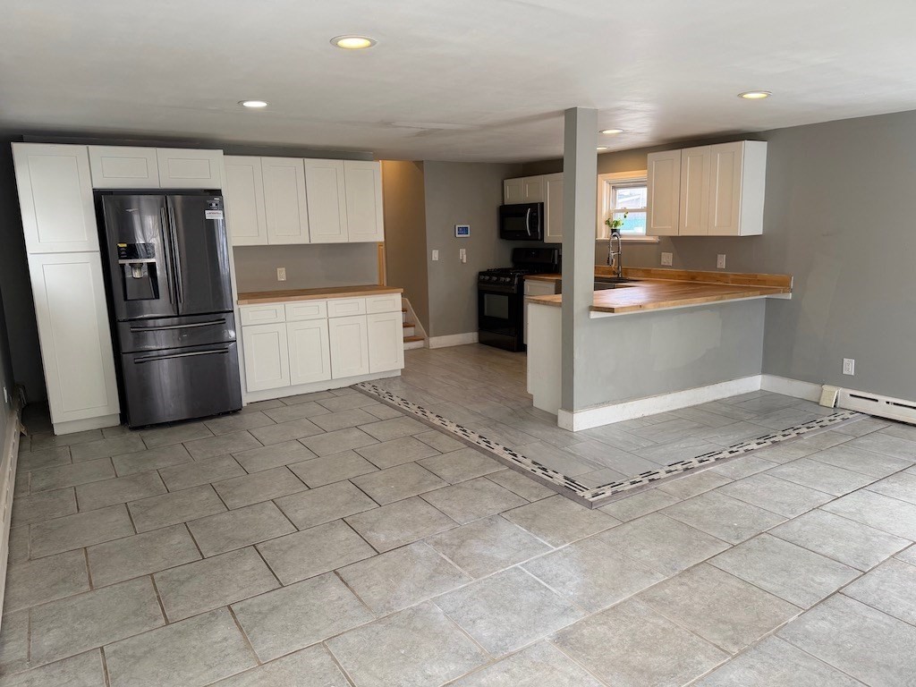 493 Rivet Street New Bedford, MA 02740 - Photo 4 of 20 a kitchen with a refrigerator and white cabinets