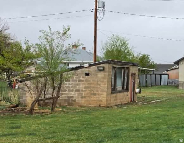 250 South Main Street Fillmore, UT 84631 - Photo 4 of 12 View of home's exterior featuring a lawn, concrete block siding, and an outbuilding