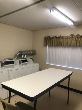 a room with a table chairs and a refrigerator