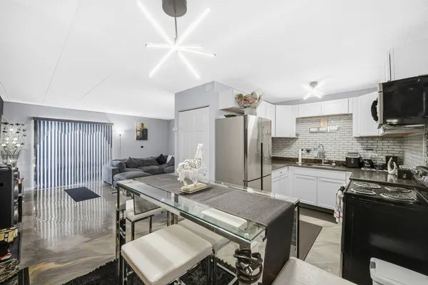 a kitchen with stainless steel appliances kitchen island granite countertop a stove a sink a refrigerator white cabinets and wooden floor