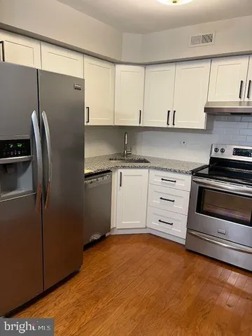 a kitchen with granite countertop a refrigerator stove and cabinets