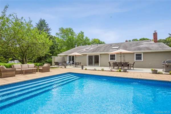 a front view of a house with swimming pool and porch with furniture