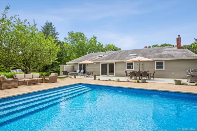 a front view of a house with swimming pool and porch with furniture