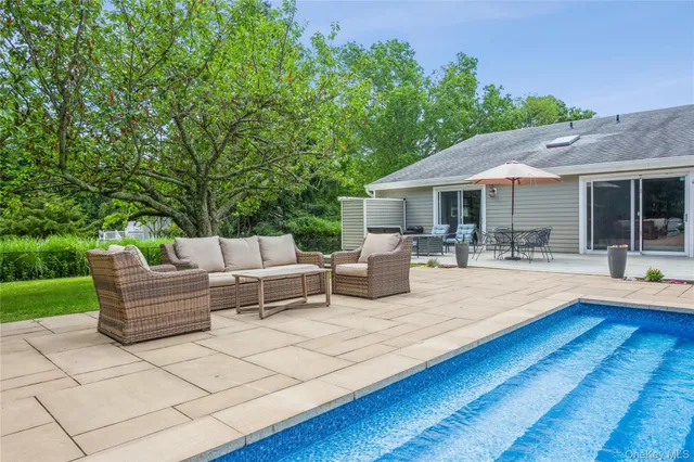 a view of a patio with couches and table and chairs with wooden fence and plants