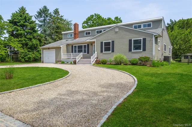 a front view of a house with a yard and potted plants