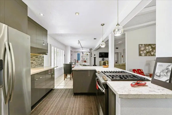 a kitchen with stainless steel appliances granite countertop a refrigerator a sink dishwasher a stove and white countertops with wooden floor