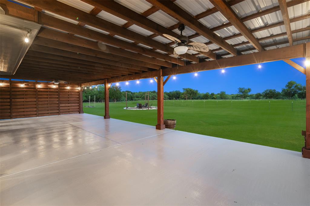 1019 Vaughan Lane Tioga, TX 76271 - Photo 33 of 40 Expansive covered patio with a smooth concrete surface, wood beam ceiling, and string lighting