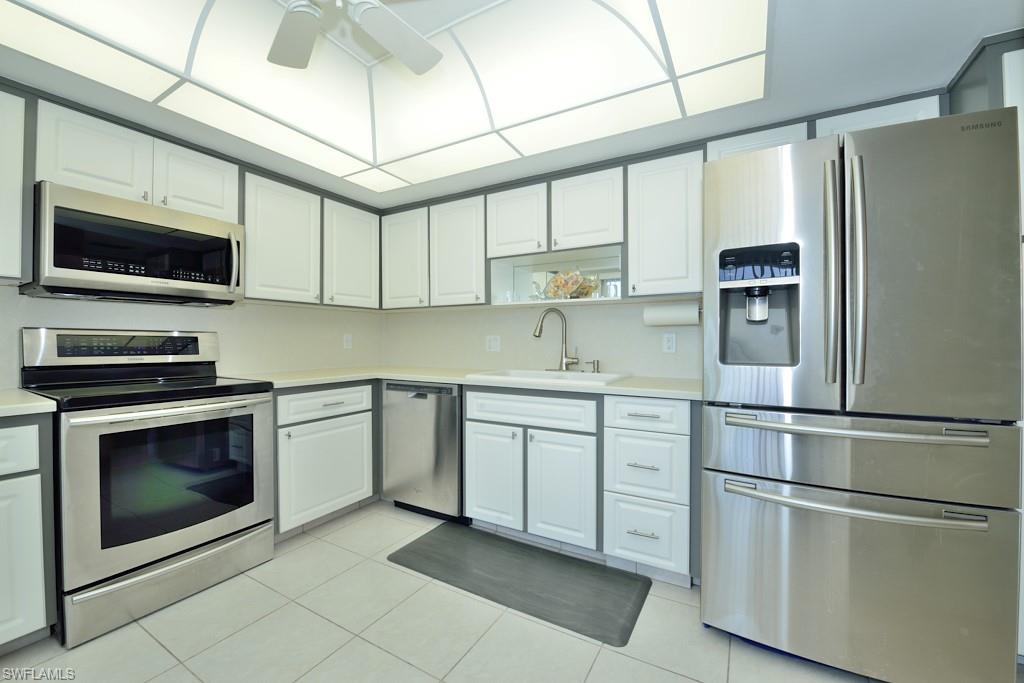 124 Penny Lane, Unit 778 Naples, FL 34112 - Photo 8 of 13 a kitchen with stainless steel appliances granite countertop a refrigerator a stove a microwave oven with white cabinets