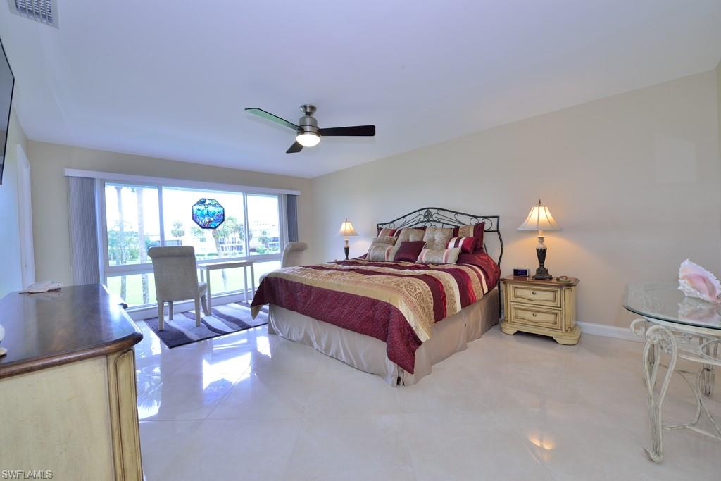 124 Penny Lane, Unit 778 Naples, FL 34112 - Photo 10 of 13 a bedroom with a bed a chandelier and a window