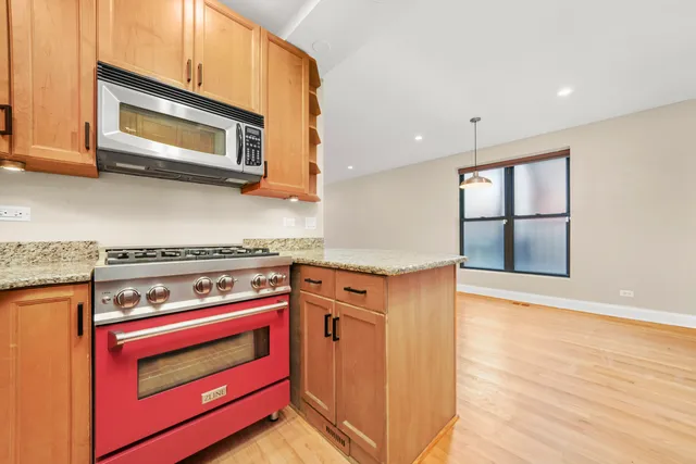 a kitchen with stainless steel appliances granite countertop a stove a microwave and a window