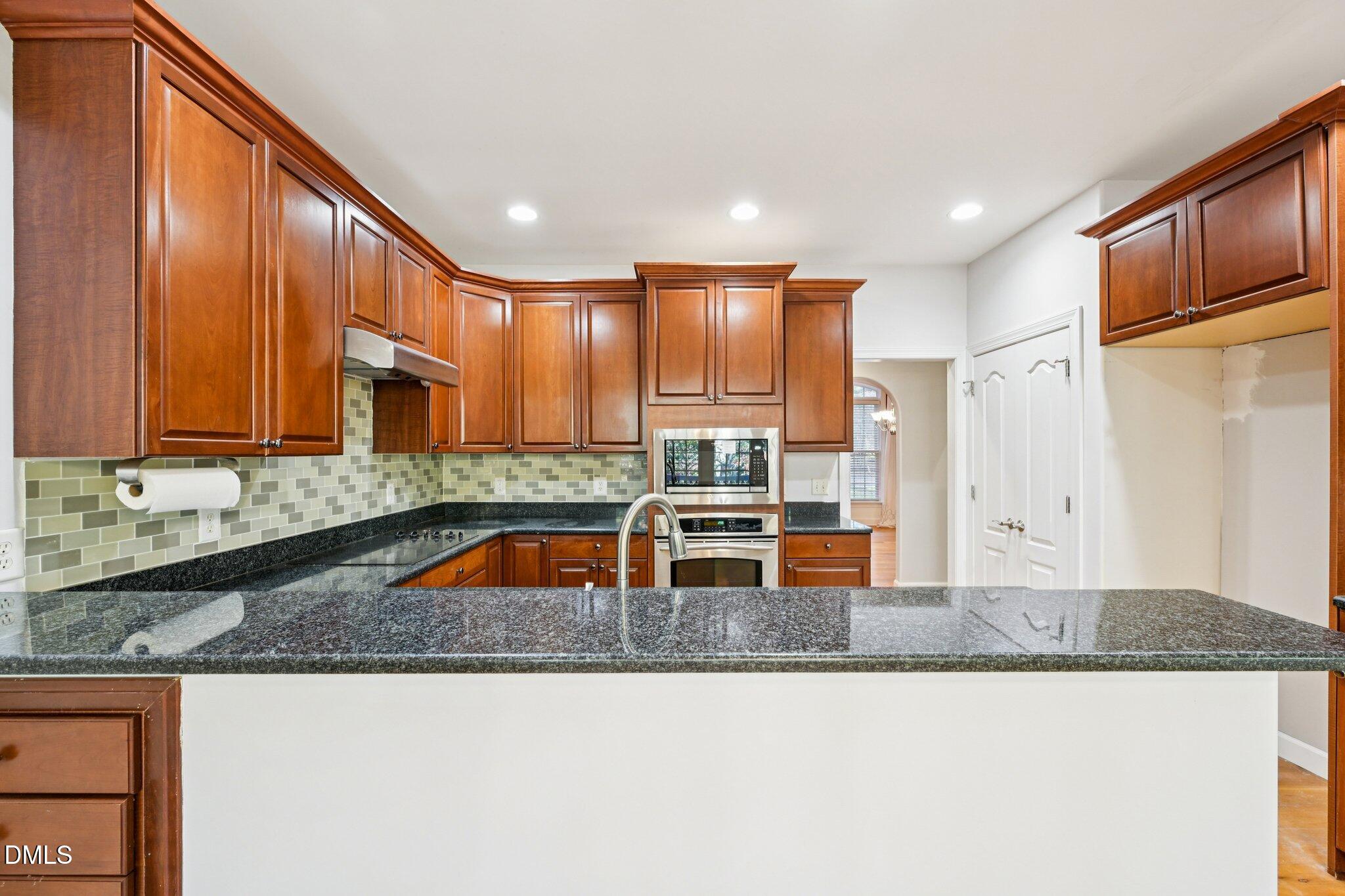 7628 Stony Hill Road Wake Forest, NC 27587 - Photo 10 of 33 a kitchen with stainless steel appliances granite countertop a sink a stove and a refrigerator with wooden cabinets