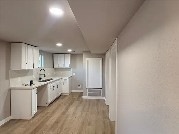 a view of a hallway with wooden floor and a kitchen