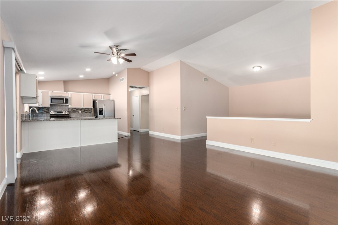 6465 West Plumcrest Road Las Vegas, NV 89108 - Photo 34 of 34 Kitchen with white cabinets, vaulted ceiling, tasteful backsplash, open floor plan, and dark wood-style flooring