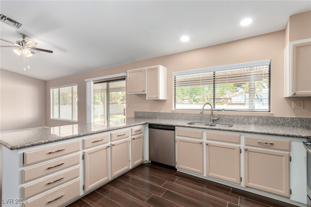 6465 West Plumcrest Road Las Vegas, NV 89108 - Photo 14 of 34 Kitchen with a peninsula, wood finish floors, light stone counters, dishwasher, and ceiling fan
