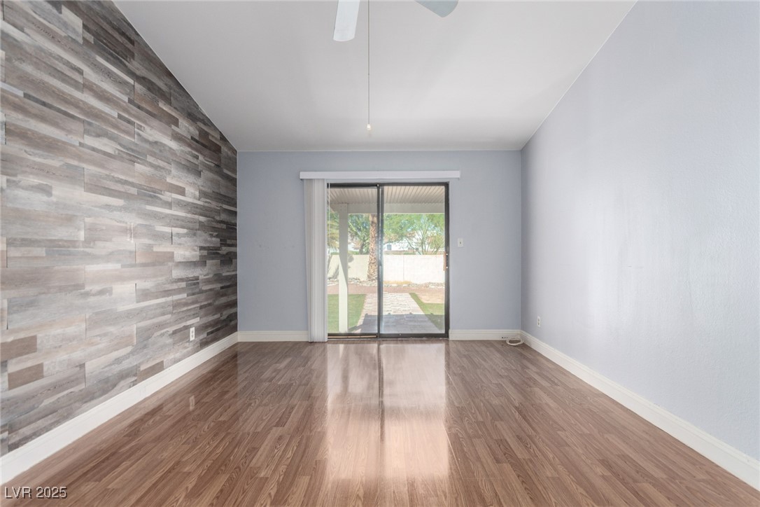 6465 West Plumcrest Road Las Vegas, NV 89108 - Photo 19 of 34 Empty room with wood walls, an accent wall, wood finished floors, and ceiling fan