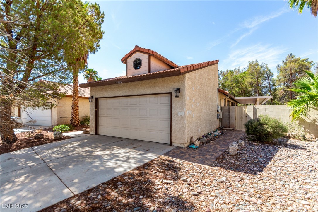 6465 West Plumcrest Road Las Vegas, NV 89108 - Photo 5 of 34 View of side of home with a garage, a tile roof, driveway, and stucco siding