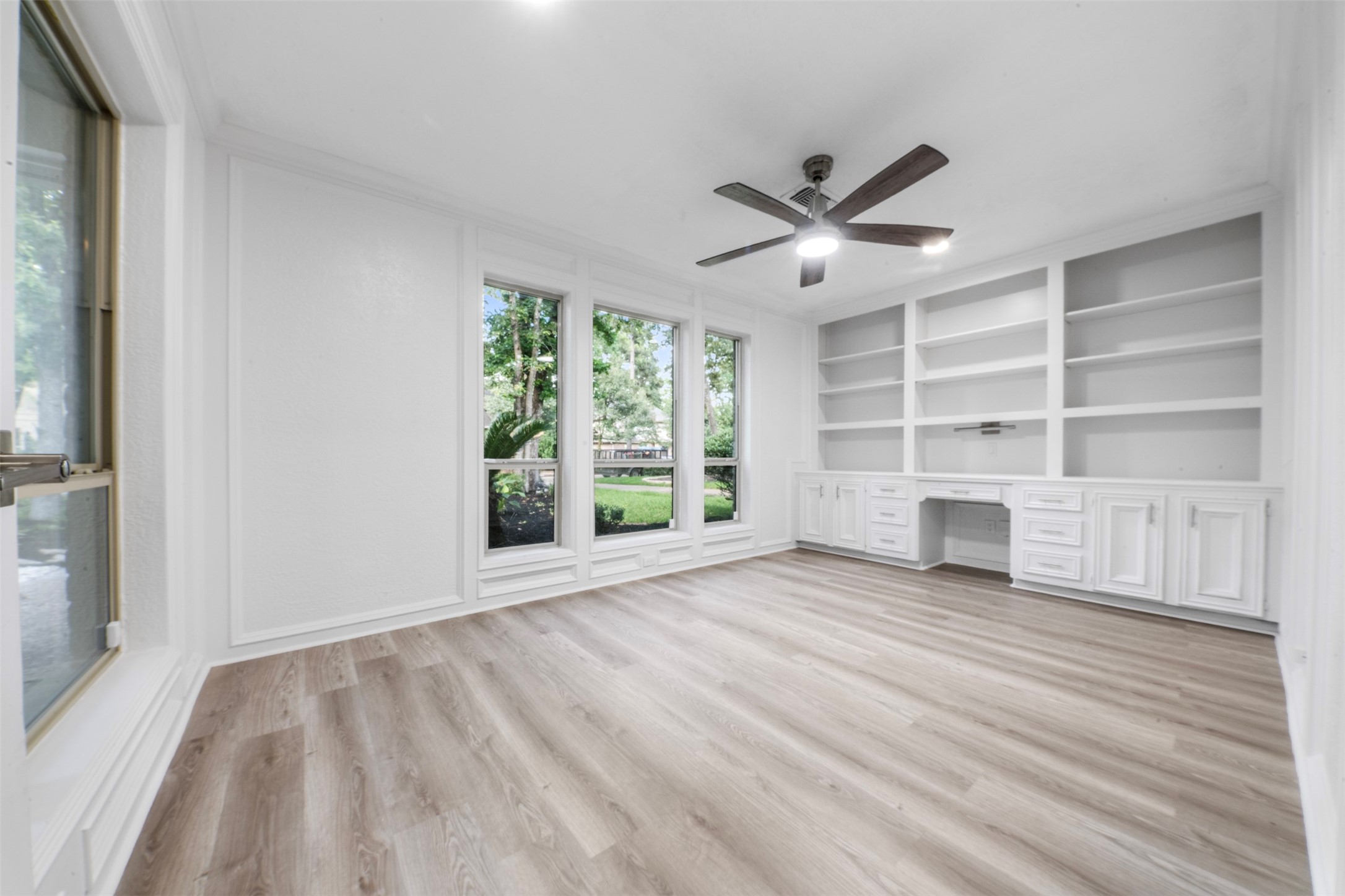 9543 Enstone Circle Spring, TX 77379 - Photo 16 of 50 Bright and spacious room featuring large windows with garden views, built-in shelves and cabinets, wood flooring, and a ceiling fan. Ideal for a home office or study.