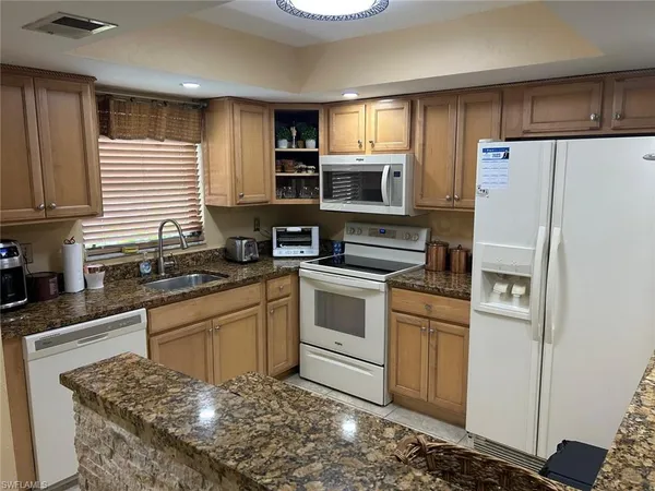 a kitchen with stainless steel appliances granite countertop a refrigerator sink stove microwave and cabinets