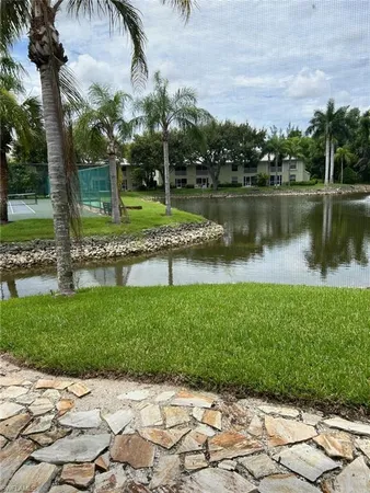 a view of a lake with a yard and large trees