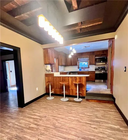 a living room with stainless steel appliances furniture a kitchen view and a fireplace