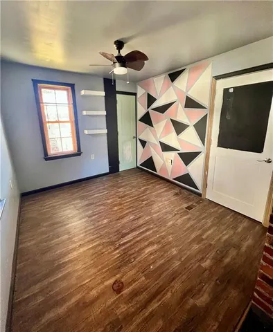 a view of an empty room with wooden floor and windows