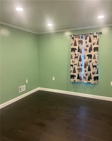 an empty room with wooden floor and fan