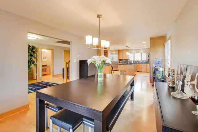 a dining room with stainless steel appliances furniture wooden floor and a kitchen view