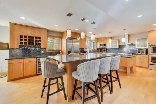 a kitchen with stainless steel appliances granite countertop table chairs sink and cabinets