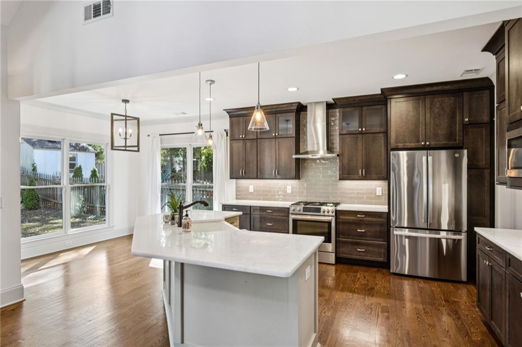 213 Ohm Avenue Avondale Estates, GA 30002 - Photo 13 of 43 a kitchen with stainless steel appliances kitchen island granite countertop a refrigerator a sink a stove and oven with wooden floor