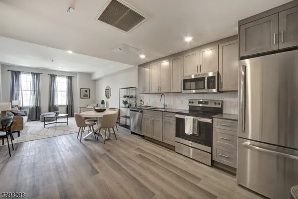 a kitchen with a refrigerator a stove top oven a dining table and chairs with wooden floor