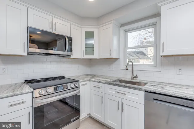 a kitchen with stainless steel appliances granite countertop white cabinets and a stove top oven