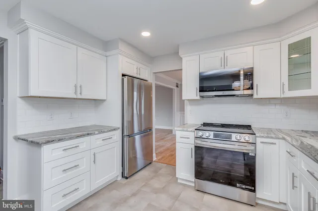 a kitchen with white cabinets and stainless steel appliances