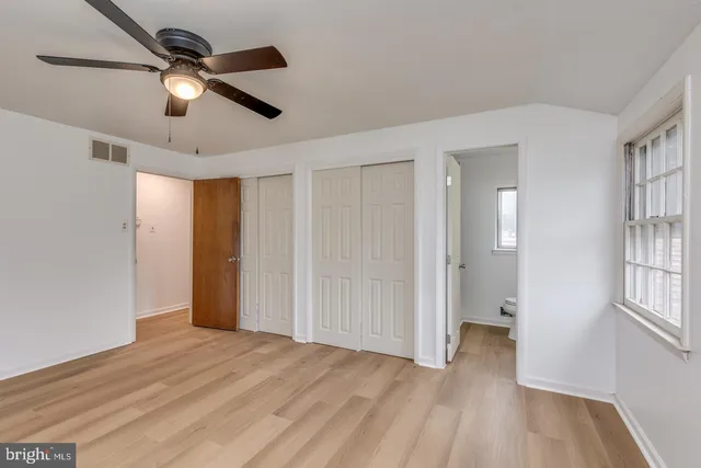 a view of empty room with wooden floor and fan