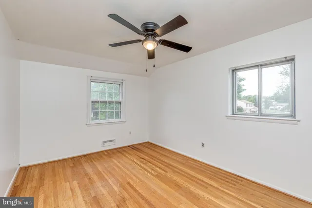 a view of empty room with wooden floor and ceiling fan