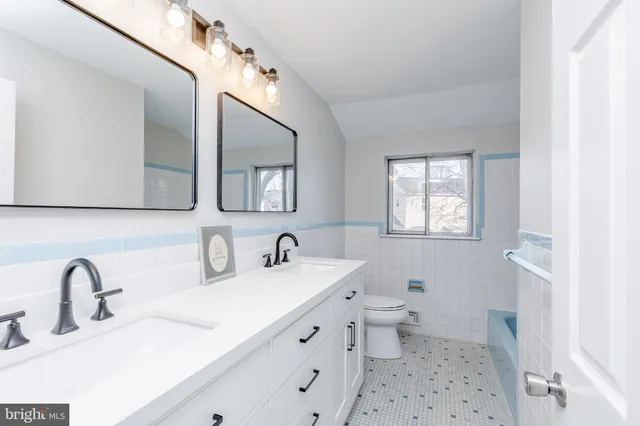 a bathroom with a double vanity sink mirror and toilet