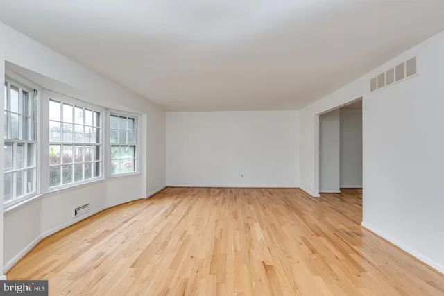 a view of an empty room with a window and wooden floor