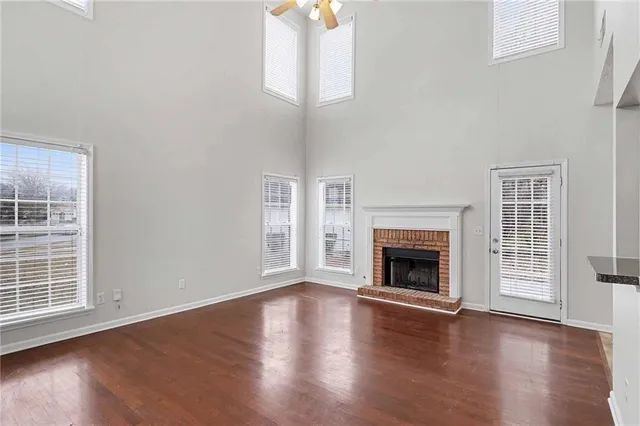 an empty room with wooden floor fireplace and windows
