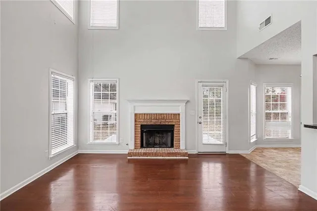 a view of an empty room with wooden floor fireplace and a window